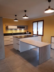 Cuisine avec meubles en laque beige amande, plan de travail en granit noir magma flammé. et îlot central, réalisée à Saint-Nazaire-en-Royans | Nodin Agencement Alixan (Drôme), Saint-Romans (Isère) et Ardèche